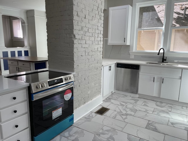 kitchen with white cabinets, stainless steel appliances, sink, and a healthy amount of sunlight