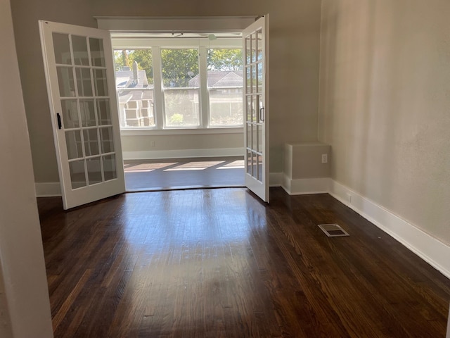 empty room featuring french doors and dark wood-type flooring