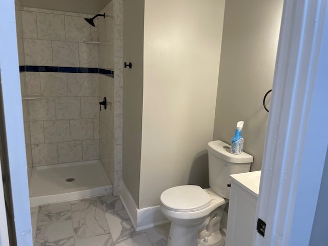 bathroom with a tile shower, vanity, and toilet