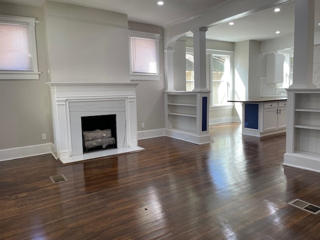 unfurnished living room featuring dark hardwood / wood-style floors and ornate columns