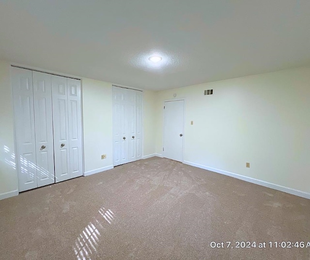 unfurnished bedroom featuring carpet floors and two closets