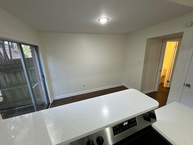 interior space with light stone countertops, vaulted ceiling, and dark hardwood / wood-style flooring