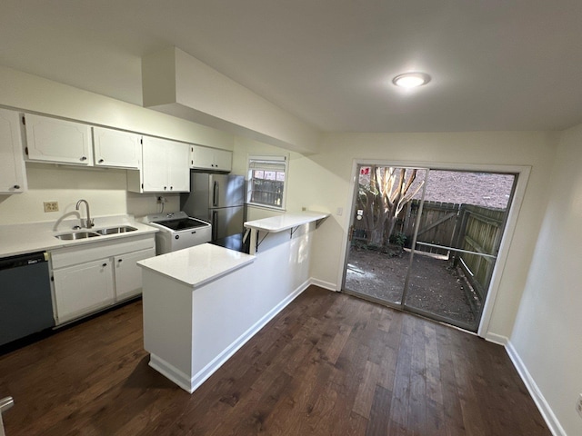 kitchen with appliances with stainless steel finishes, white cabinetry, kitchen peninsula, dark hardwood / wood-style flooring, and sink