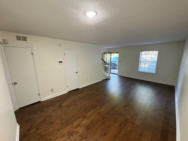 empty room with a textured ceiling and dark hardwood / wood-style flooring