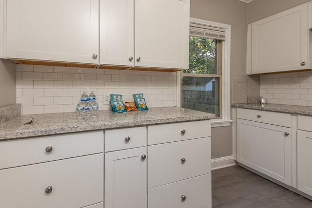 kitchen featuring light stone counters, backsplash, and white cabinetry