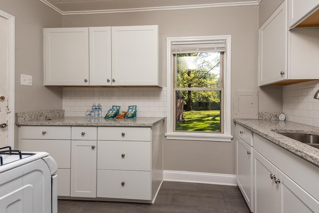 kitchen featuring light stone counters, white cabinets, sink, tasteful backsplash, and crown molding