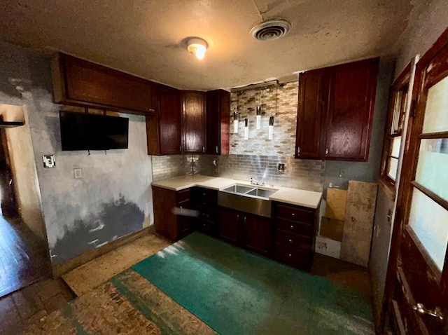 kitchen featuring a textured ceiling, decorative backsplash, and sink