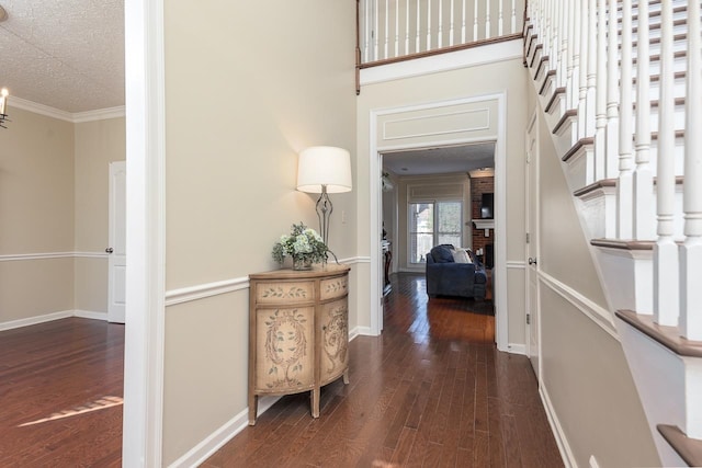 hall featuring dark wood-type flooring, a textured ceiling, and crown molding