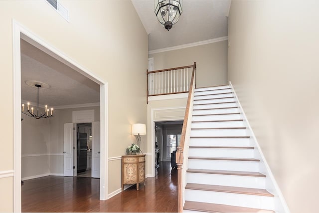 staircase with an inviting chandelier, wood-type flooring, and crown molding