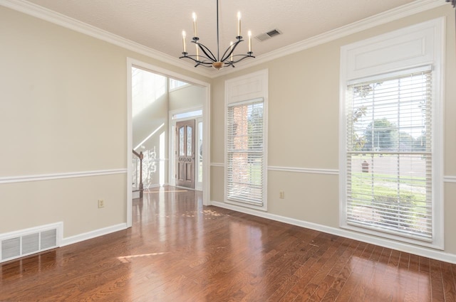 spare room featuring wood-type flooring, a textured ceiling, crown molding, and an inviting chandelier