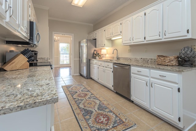 kitchen with white cabinets, light stone counters, crown molding, and stainless steel appliances