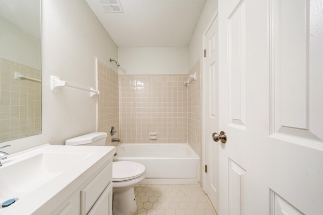 full bathroom featuring a textured ceiling, tiled shower / bath combo, vanity, and toilet