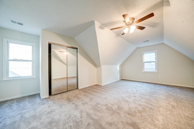 bonus room featuring a textured ceiling, vaulted ceiling, ceiling fan, and light carpet