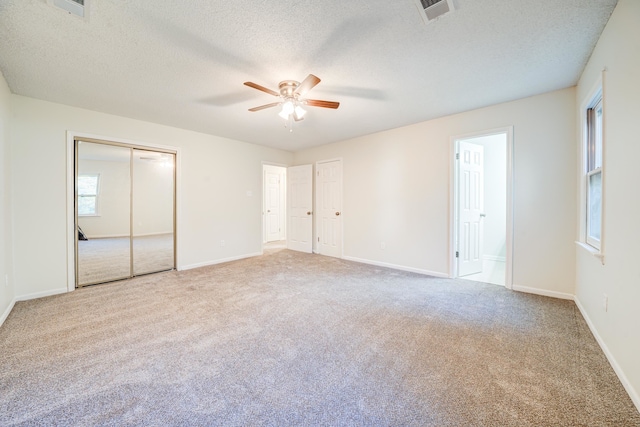 unfurnished bedroom with ceiling fan, light colored carpet, and a textured ceiling