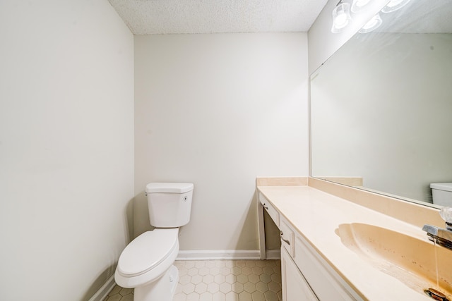 bathroom with vanity, toilet, and a textured ceiling