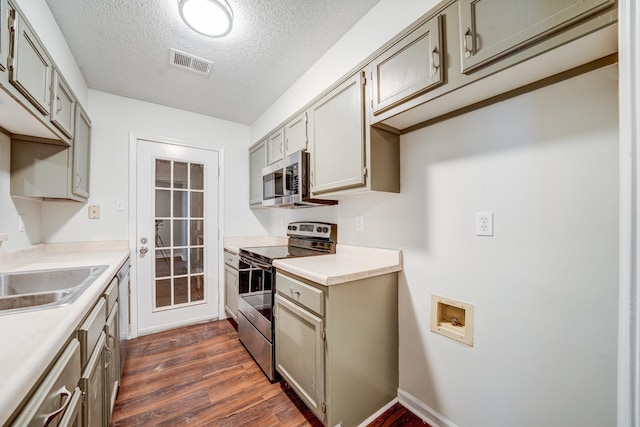 kitchen with a textured ceiling, appliances with stainless steel finishes, dark wood-type flooring, and sink