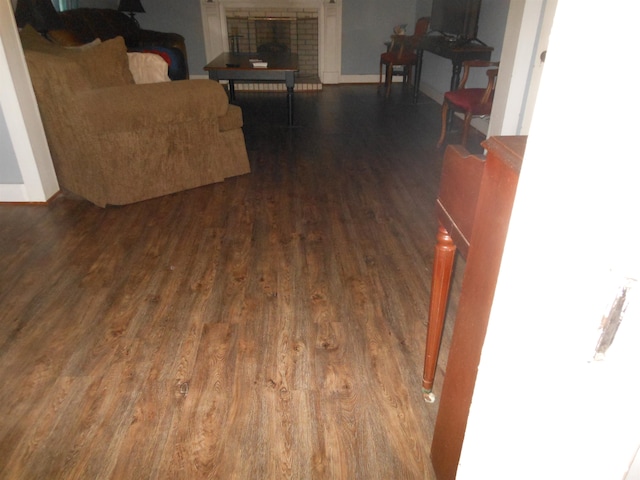 living room with dark hardwood / wood-style flooring and a brick fireplace