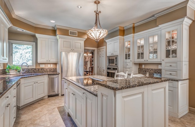 kitchen featuring appliances with stainless steel finishes, hanging light fixtures, white cabinets, a kitchen island, and sink