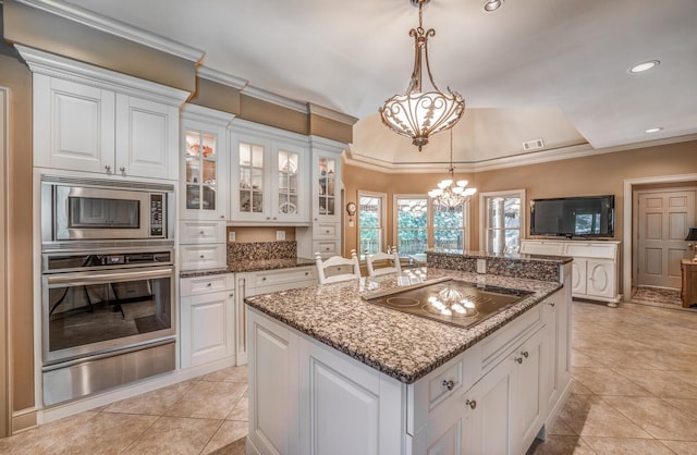 kitchen featuring a kitchen island, decorative light fixtures, white cabinetry, black electric cooktop, and a notable chandelier