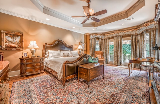 bedroom with ornamental molding, ceiling fan, a raised ceiling, and hardwood / wood-style flooring