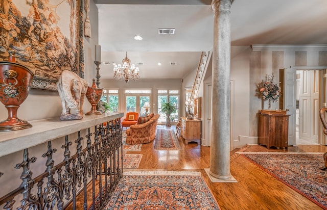 hallway featuring a notable chandelier, ornamental molding, hardwood / wood-style floors, and ornate columns