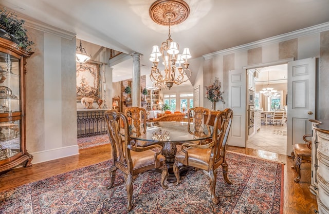 dining space featuring light hardwood / wood-style flooring, crown molding, decorative columns, and a chandelier