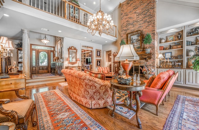 living room with ornate columns, ornamental molding, light wood-type flooring, and a high ceiling