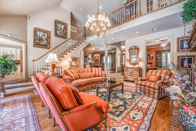 living room with ornate columns, hardwood / wood-style flooring, ornamental molding, and high vaulted ceiling