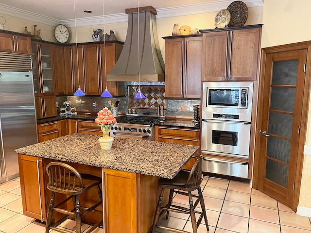 kitchen with exhaust hood, built in appliances, a breakfast bar area, and a kitchen island