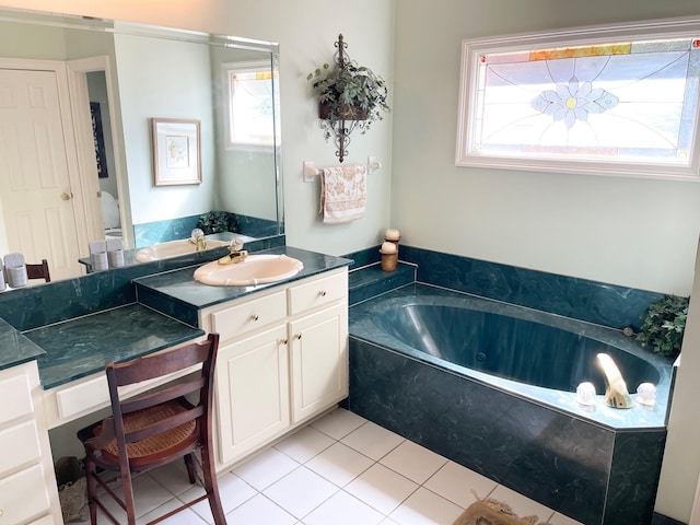 bathroom featuring tile patterned flooring, tiled tub, plenty of natural light, and vanity