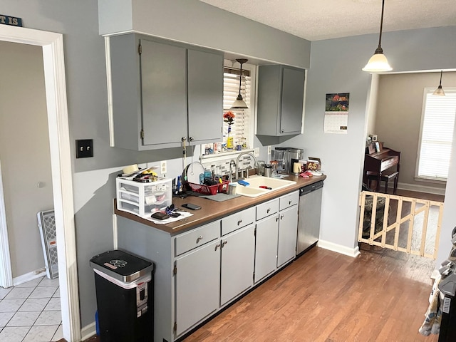 kitchen featuring gray cabinetry, dishwasher, hanging light fixtures, and sink