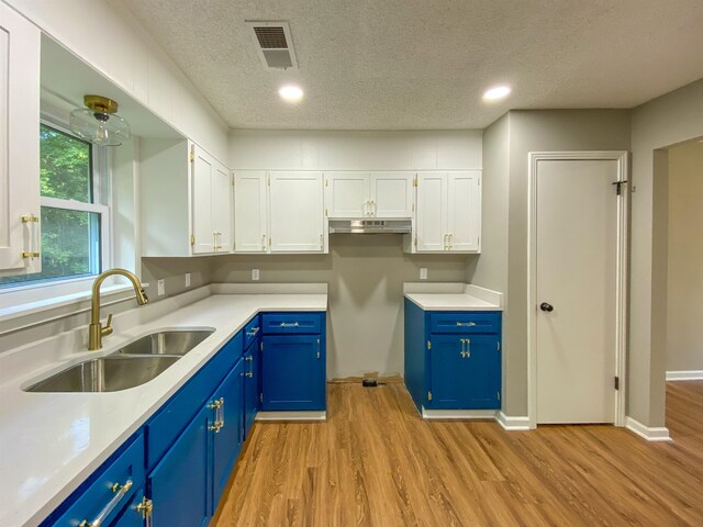 kitchen with light hardwood / wood-style floors, blue cabinets, sink, and white cabinetry