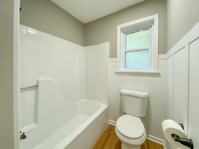 bathroom with wood-type flooring, shower / bathing tub combination, and toilet