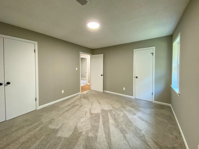 unfurnished bedroom with a textured ceiling and light colored carpet