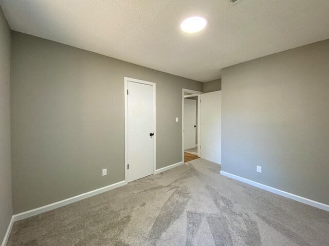 unfurnished bedroom featuring a textured ceiling, a closet, and carpet flooring