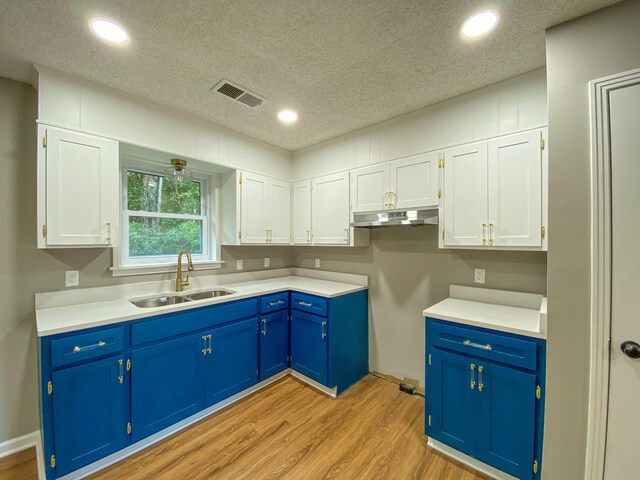 kitchen featuring blue cabinetry, light hardwood / wood-style flooring, sink, white cabinets, and a textured ceiling