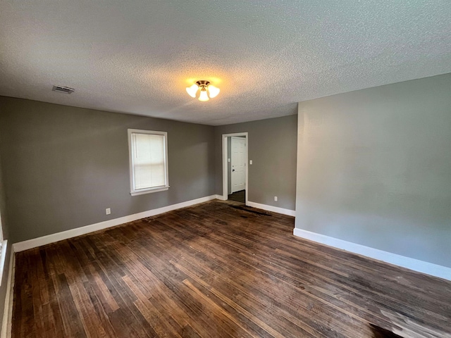 empty room featuring a textured ceiling and dark hardwood / wood-style floors