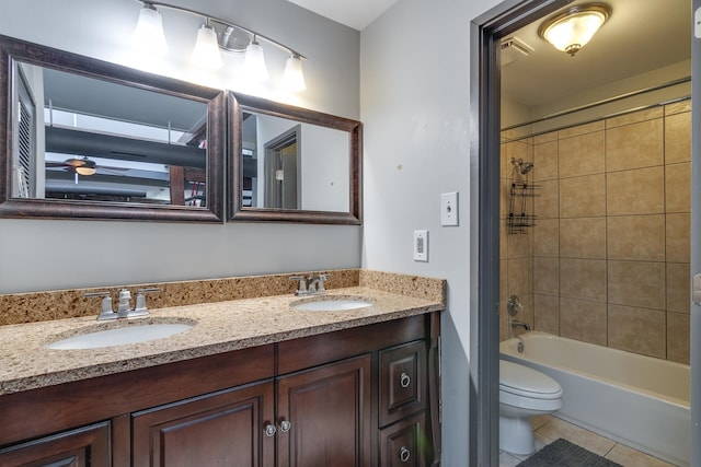 full bathroom featuring tiled shower / bath, vanity, toilet, and tile patterned floors