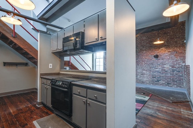 kitchen with dark hardwood / wood-style floors, brick wall, and black appliances