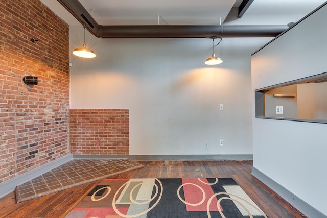 unfurnished living room featuring beamed ceiling, brick wall, and dark hardwood / wood-style flooring