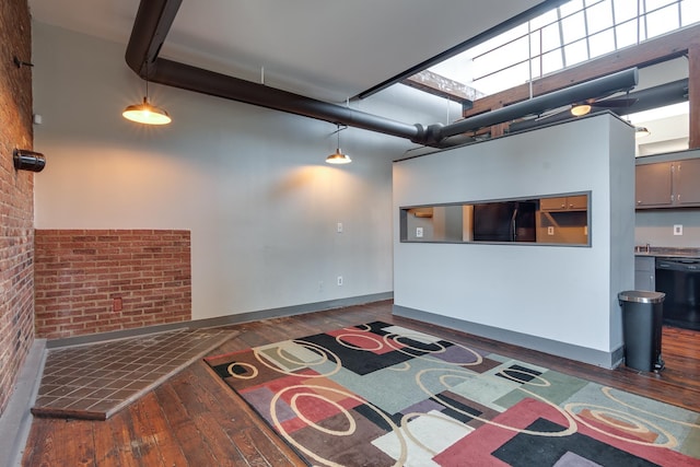 living room with dark hardwood / wood-style floors, brick wall, and a high ceiling