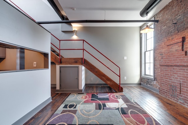 interior space featuring brick wall, dark hardwood / wood-style flooring, and a high ceiling