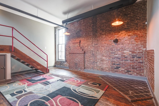 unfurnished living room with dark hardwood / wood-style floors and brick wall