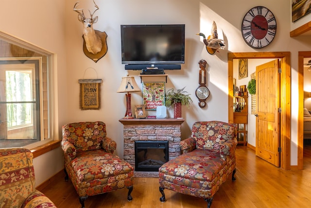 living area with a stone fireplace and hardwood / wood-style floors