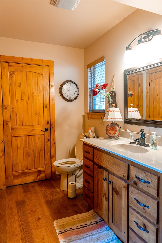 bathroom with hardwood / wood-style flooring, vanity, and toilet