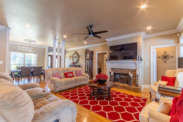 living room with a stone fireplace, crown molding, hardwood / wood-style flooring, and ceiling fan