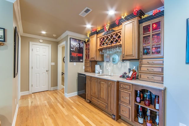 bar featuring sink, dishwasher, light stone countertops, crown molding, and light hardwood / wood-style floors