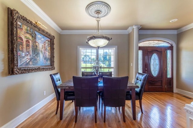 dining area featuring ornate columns, hardwood / wood-style floors, and ornamental molding