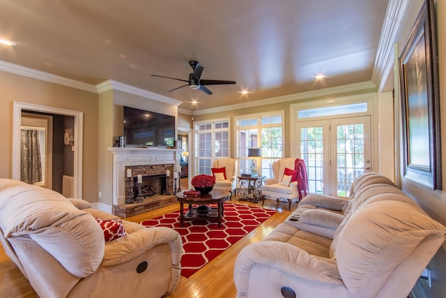 living room with radiator, ceiling fan, crown molding, a fireplace, and hardwood / wood-style flooring