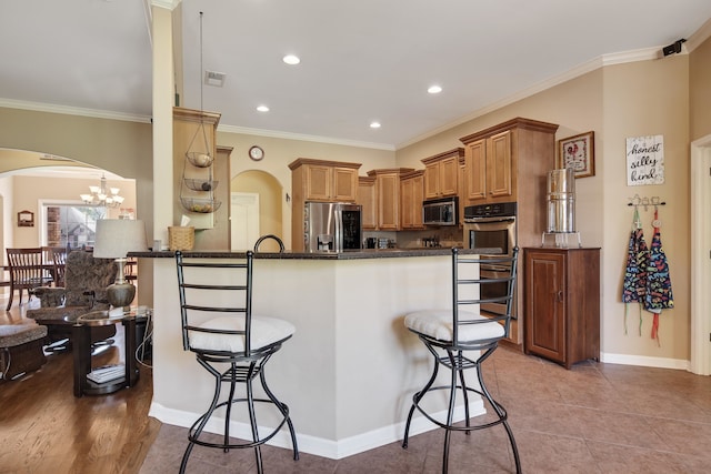 kitchen with a breakfast bar, ornamental molding, kitchen peninsula, appliances with stainless steel finishes, and light tile patterned floors